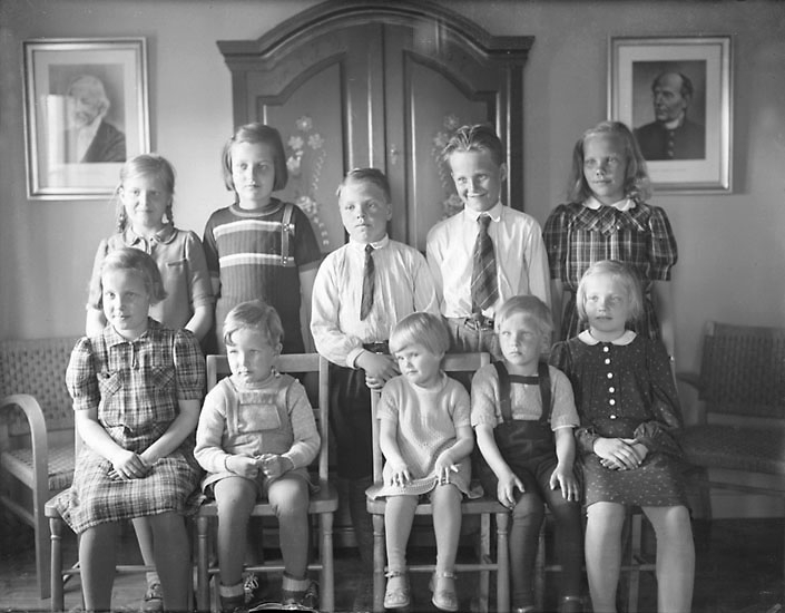 Svartvitt grupporträtt av tio barn som småleende eller blygt tittar in i kameran. 