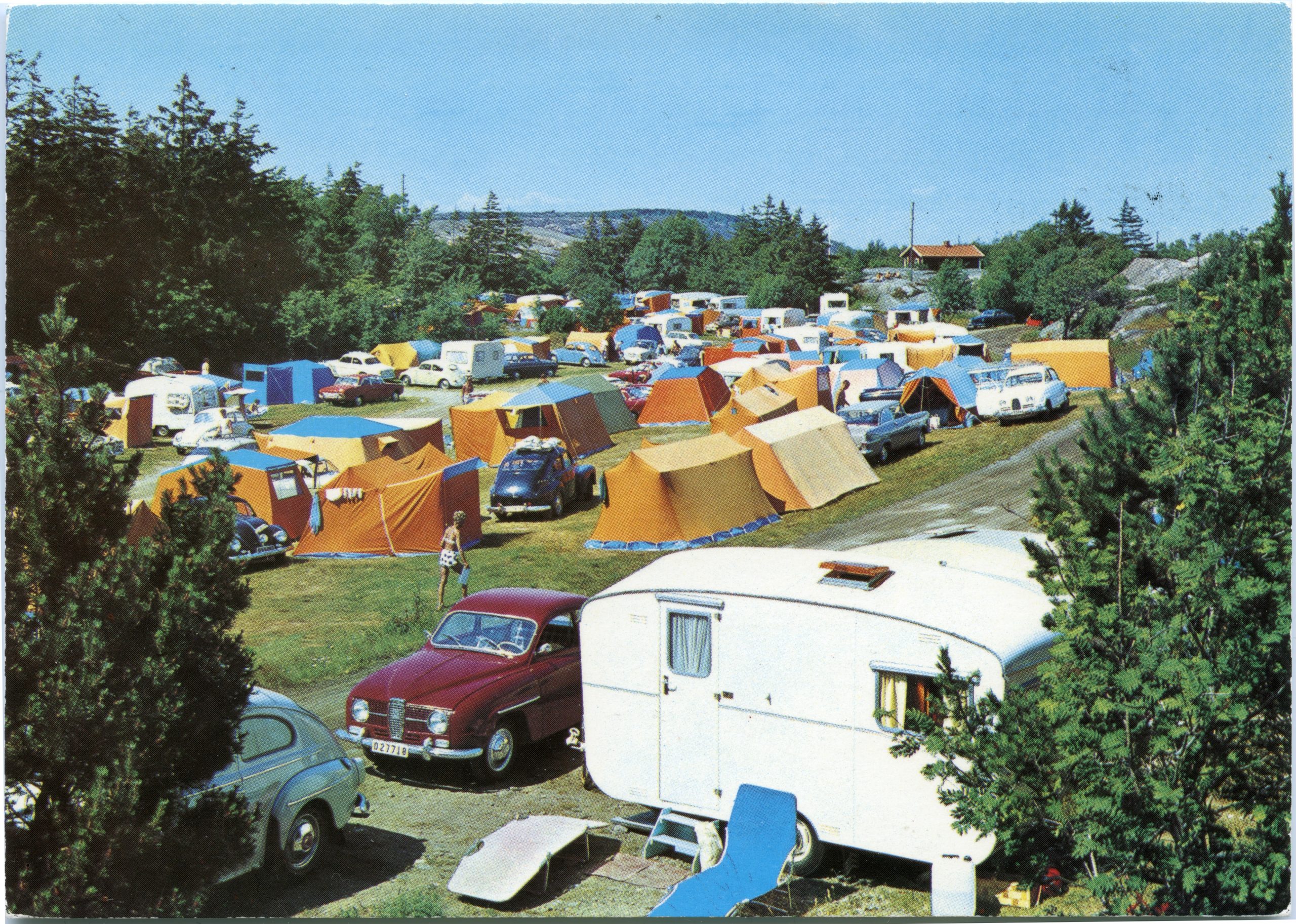 Färfotografi. Tält och husvagnar uppställda på en campingplats.