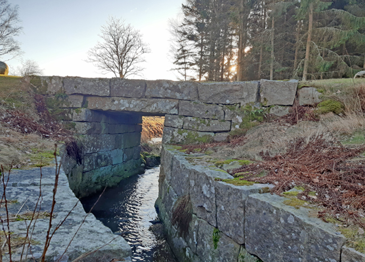 Färgfoto av välbyggd stenbro och stensatt kanal.
