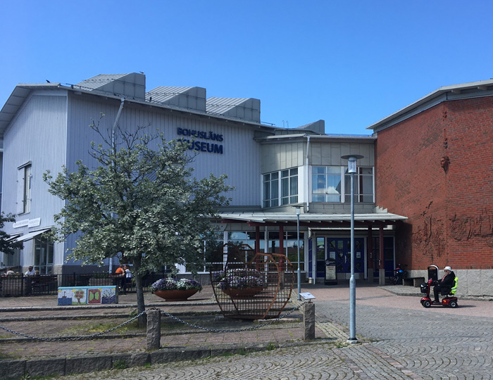 Foto av kvinna i permobil framför Bohusläns museums entré.