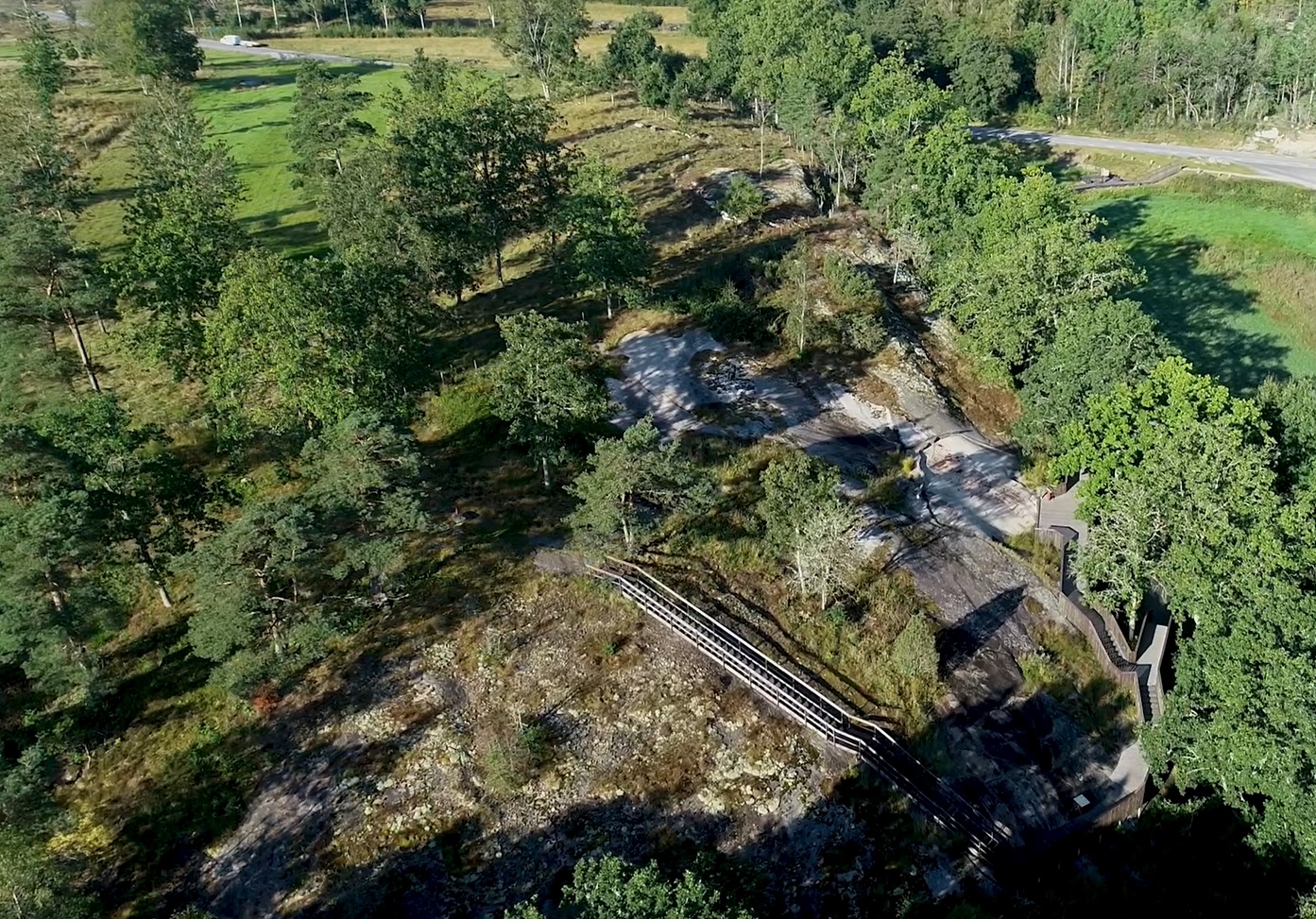 Färgfoto från luften av berg med gles lövskog och en trappa.