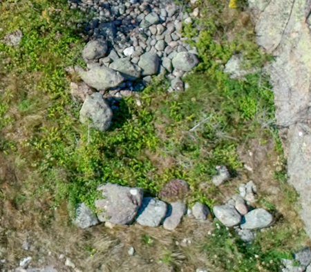 Mot berget ligger stenar i rad som bildar en fyrkantigt rum.