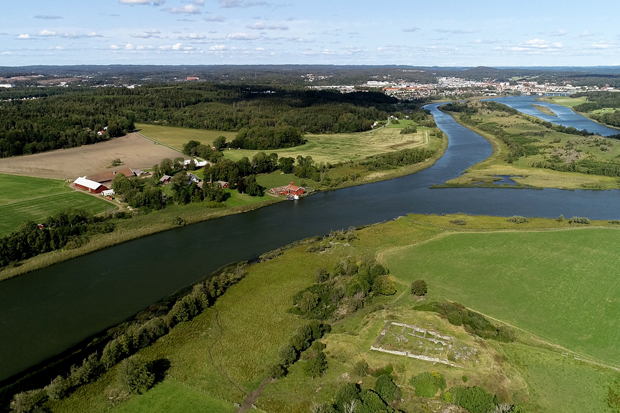 Färgfoto av älv med grönskande jordbruksmark på sidorna.