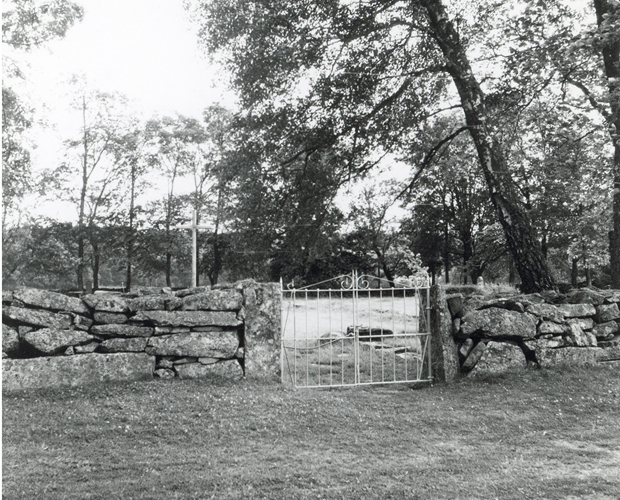 Svartvitt foto med vit järngrind och stenmur.