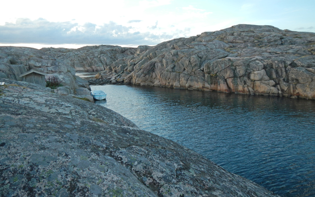Färgfoto av branta bergssidor som omger ett smalt sund.
