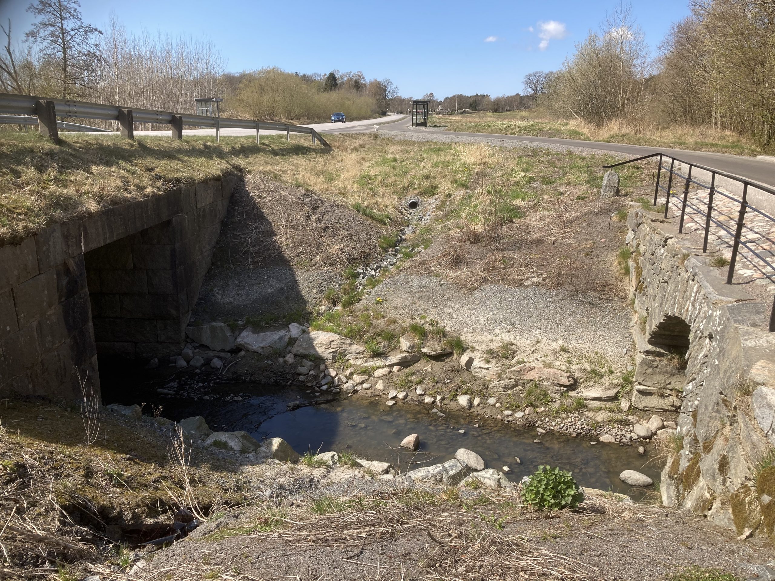 Färgfoto med två broar intill varandra, en betongbro och en välvd stenbro.