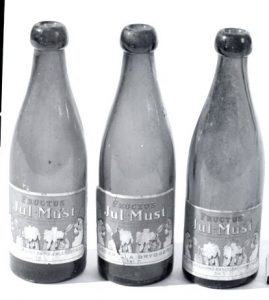 Svartvitt foto av tre glasflaskor märkta med Julmust-ektiketter.