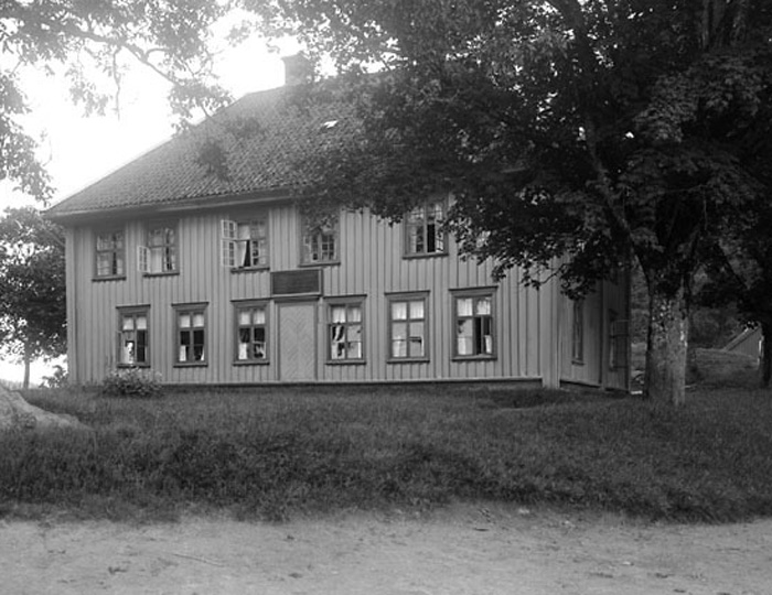 Svartvitt foto på en träbyggnad i två våningar. 