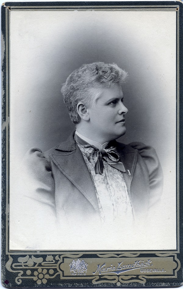 Svartvitt foto. Bröstbild av kvinna med kort frisyr och ansiktet i profil.
