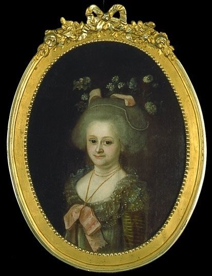 Porträtt i oval ram. Bröstbild av kvinna med djupt ringad klänning avskuren under bysten och försedd med stor rosett.