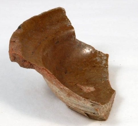Färgfoto med del av ett brun keramikfat.