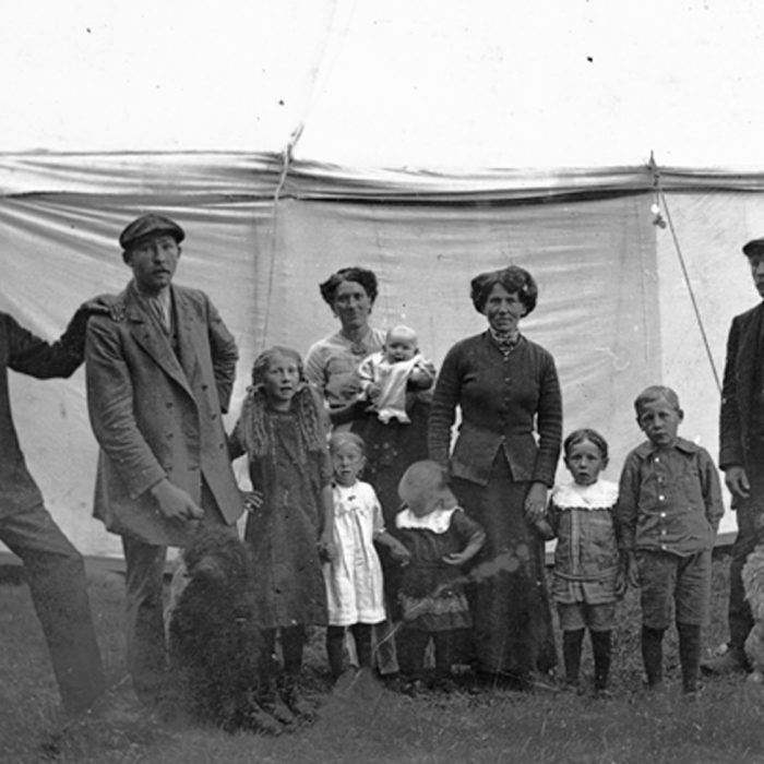 Svartvitt foto på vuxna, barn och två hundar framför ett cirkustält