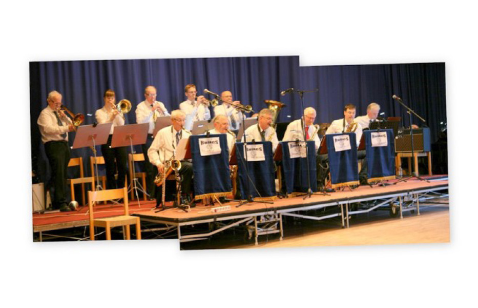 Foto. Storband på scen med blå gradäng i bakgrunden. Elva personer i medelåldern som spelar blåsinstrument.