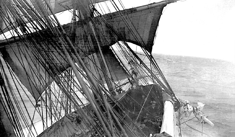 Svartvitt foto. Detalj av lutande fartyg med fem sjömän på däcket.