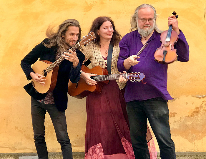 Tre personer, en man, en kvinna och en annan man som alla håller i instrument.