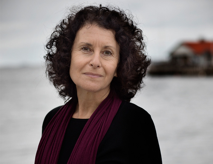 En mörkhårig kvinna med svart tröja. Om halsen har hon en lila scarf.