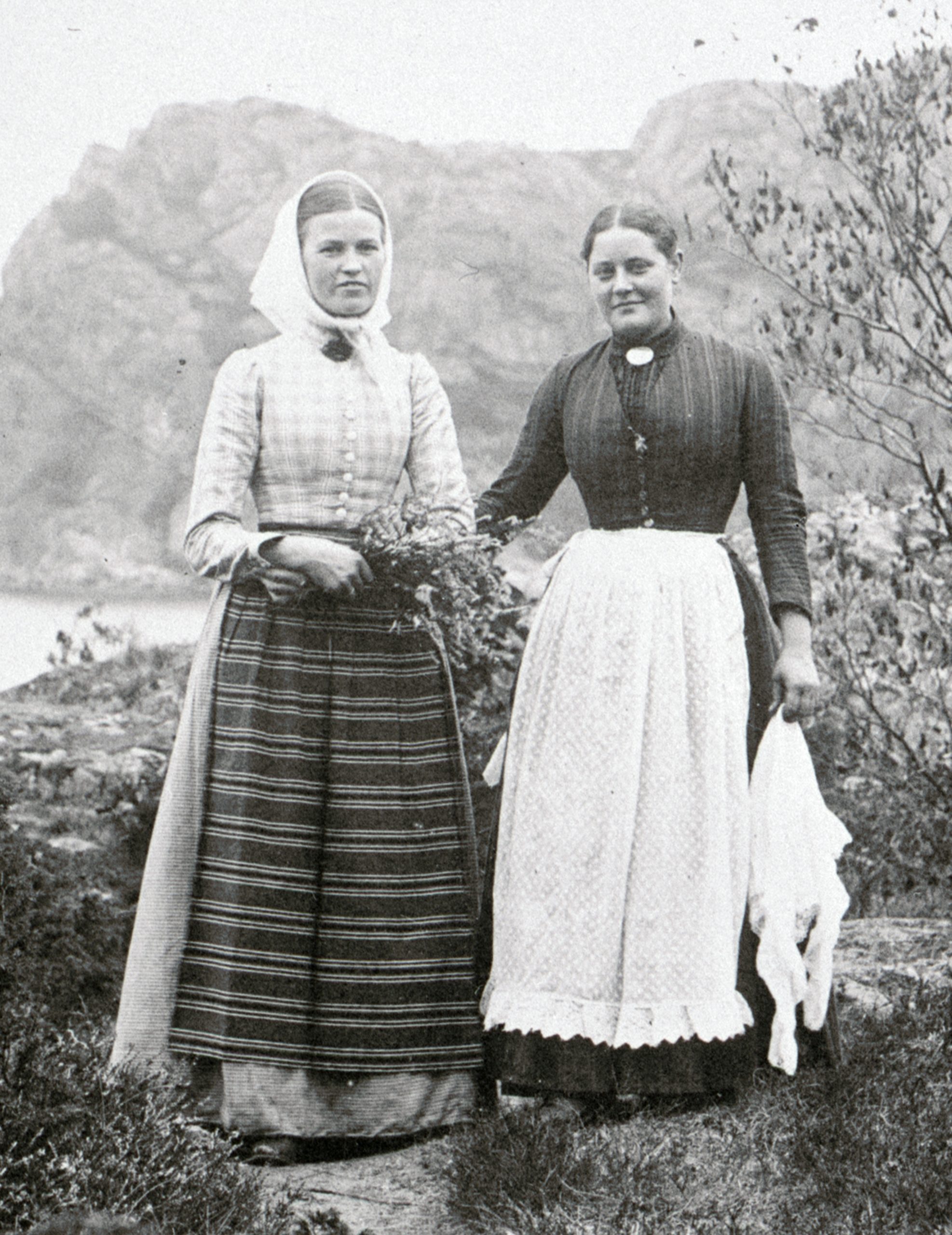Svartvitt foto. Två kvinnor sekelskifteskläder på promenadstig.