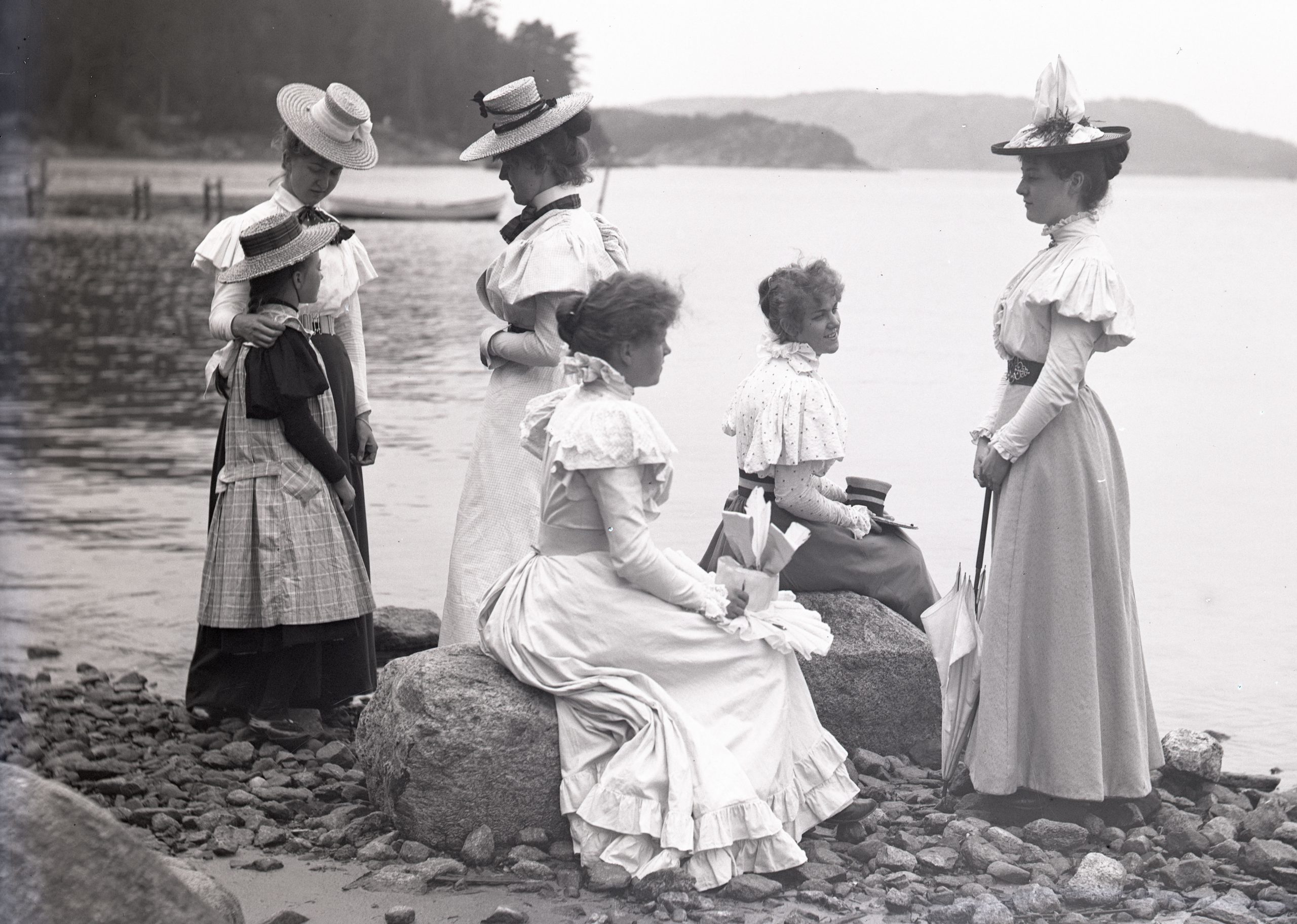 Svartvitt foto. En grupp med fem unga kvinnor och en flicka i tioårsåldern vid stranden.
