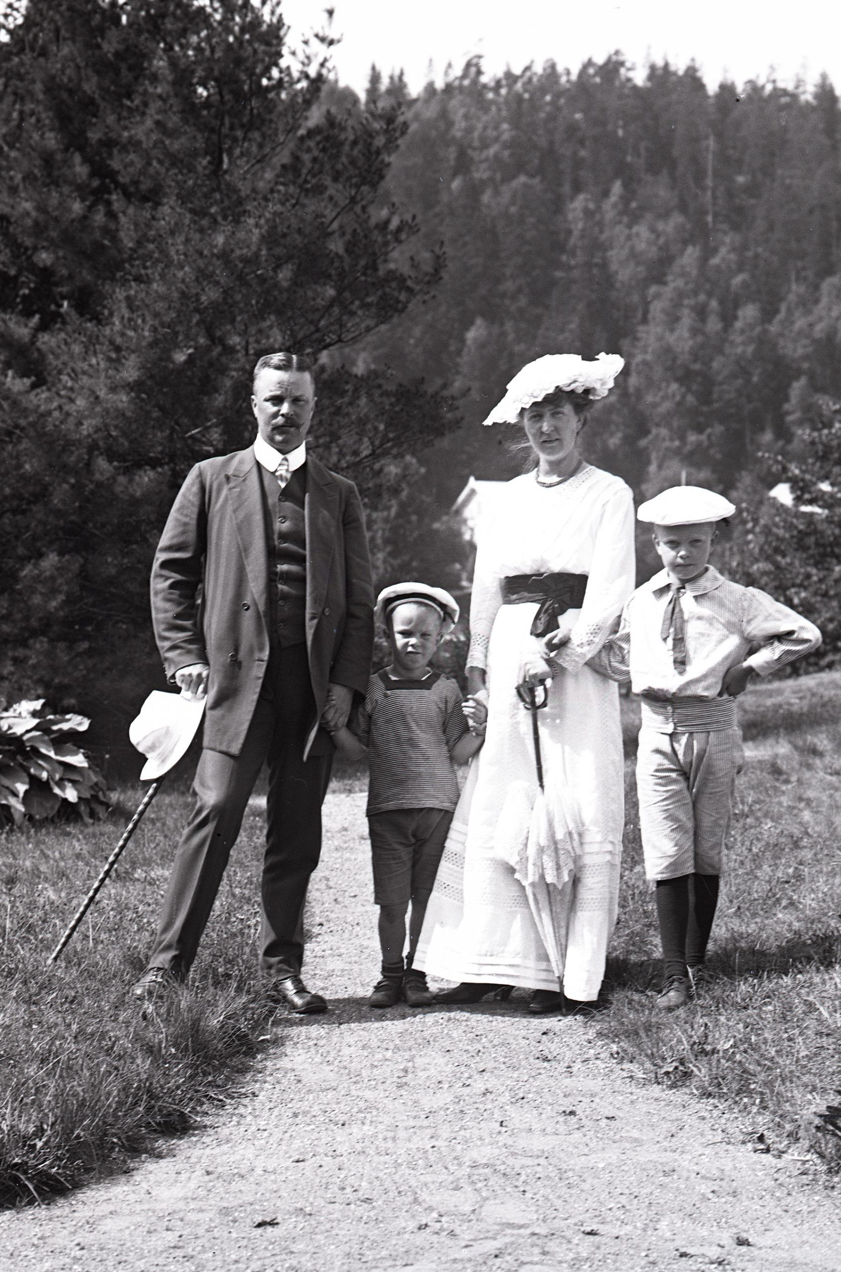 Svartvitt foto. Familjgrupp med två pojkar cirka 6 till 8 år gammal på en promenadväg.