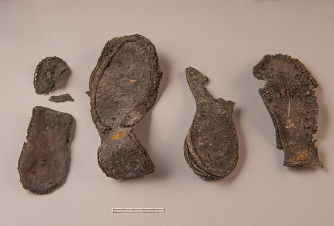 Foto. Fyra fragment av skosulor av läder.