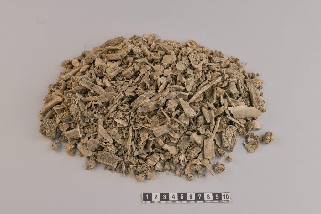 Foto. En hög, cirka 60 cm i omkrets, med små bitar av brända ben. 