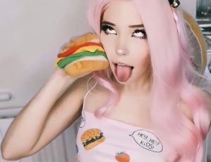 Foto. Kvinna med rosa hår och slätt ansikte himlar med ögonen och räcker gapar med tungan utsträckt i handen håller hon upp en hamburgare.
