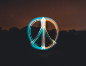 Foto. Peace-tecken i laserljus blått och vitt i kvällsljus utomhus.