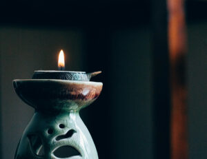 Foto. Ett tänt värmeljus på en ljusstake i keramik