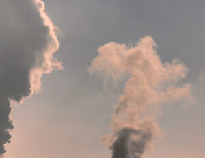 Foto. Blådisig himmel med rök som bolmar.