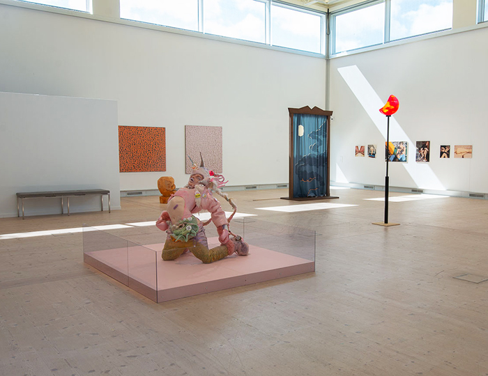Bild som visar konsthallen på Bohusläns museum. I förgrunden syns en skulptur föreställande en människa och i bakgrunden flera målningar. Rummet har ett ljust trägolv och vita väggar. Upptill i bild fönster med ljus som strilar in och belyser ena väggen.