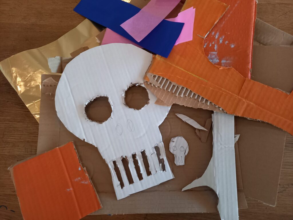Foto. En vit dödskalle-formad mask utklippt ur kartong.