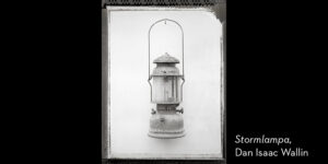 Svartvitt foto. En fotogenlampa upphäng mot vit bakgrund.