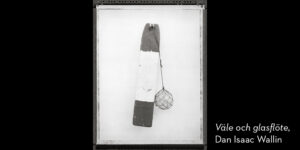 Svartvitt foto. En träbit målad i mörkare färg i ändarna och vit färg i mitten med ett sfäriskt glassänke fäst i rep.